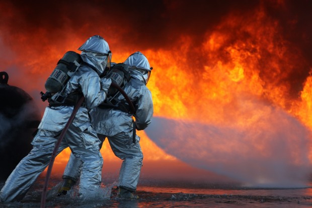 Two Marines with Marine Wing Support Squadron 271 fight the giant flames and intense heat to put out a fuel fire that was started for training purposes at the station aircraft rescue and firefighting training pit, March 19. (Photo by Lance Cpl. Cory D. Polom)