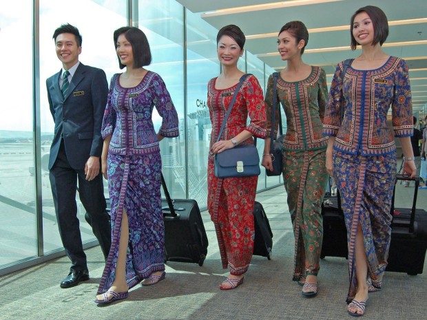 Crew uniform colours of Singapore Airlines. L-R. Leading Steward (LS, green tie), In Flight Supervisor female (IFSS, purple Sarong Kebaya), Chief Stewardess (CSS, Red), Leading Stewardess (LSS, Green), Flight Stewardess (FSS, Blue). The picture also represents the three major ethnic groups of Singapore. Chinese, Indians, Malays. Photo courtesy Changi airport.